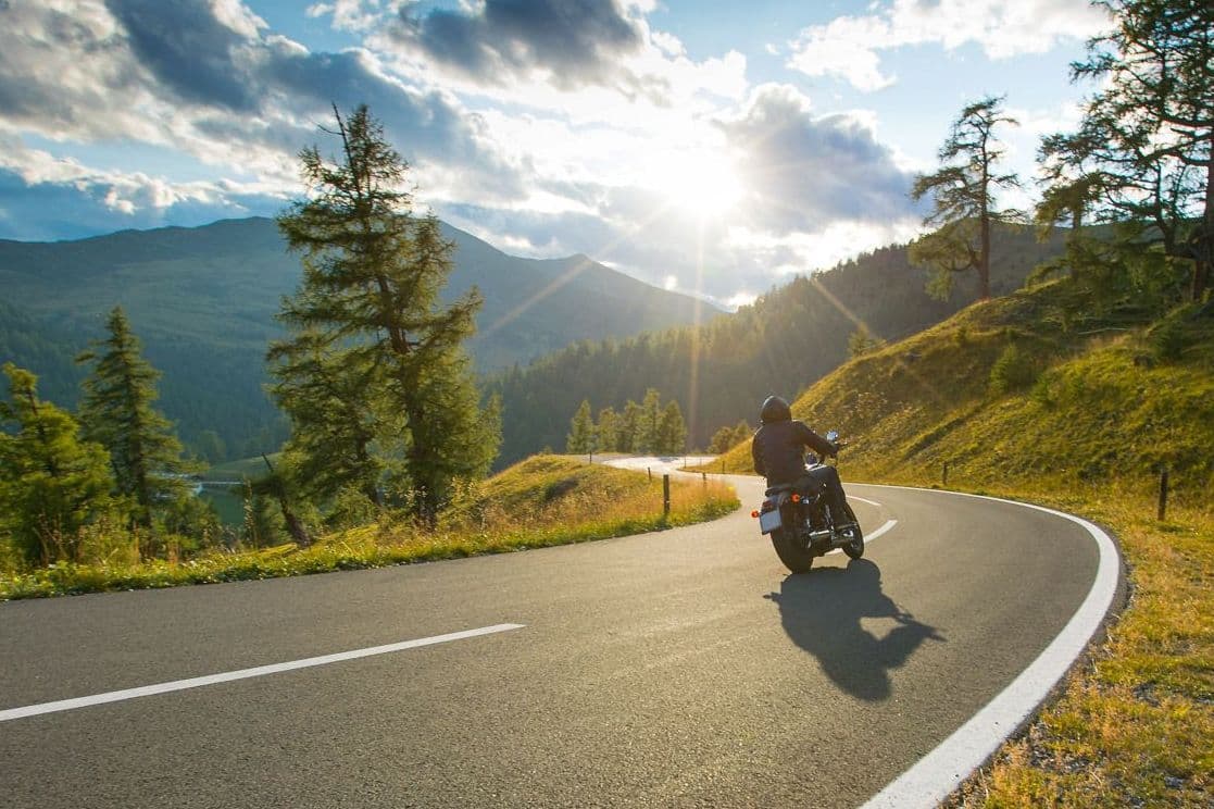 Motorradfahrer fährt in malerischer Umgebung.