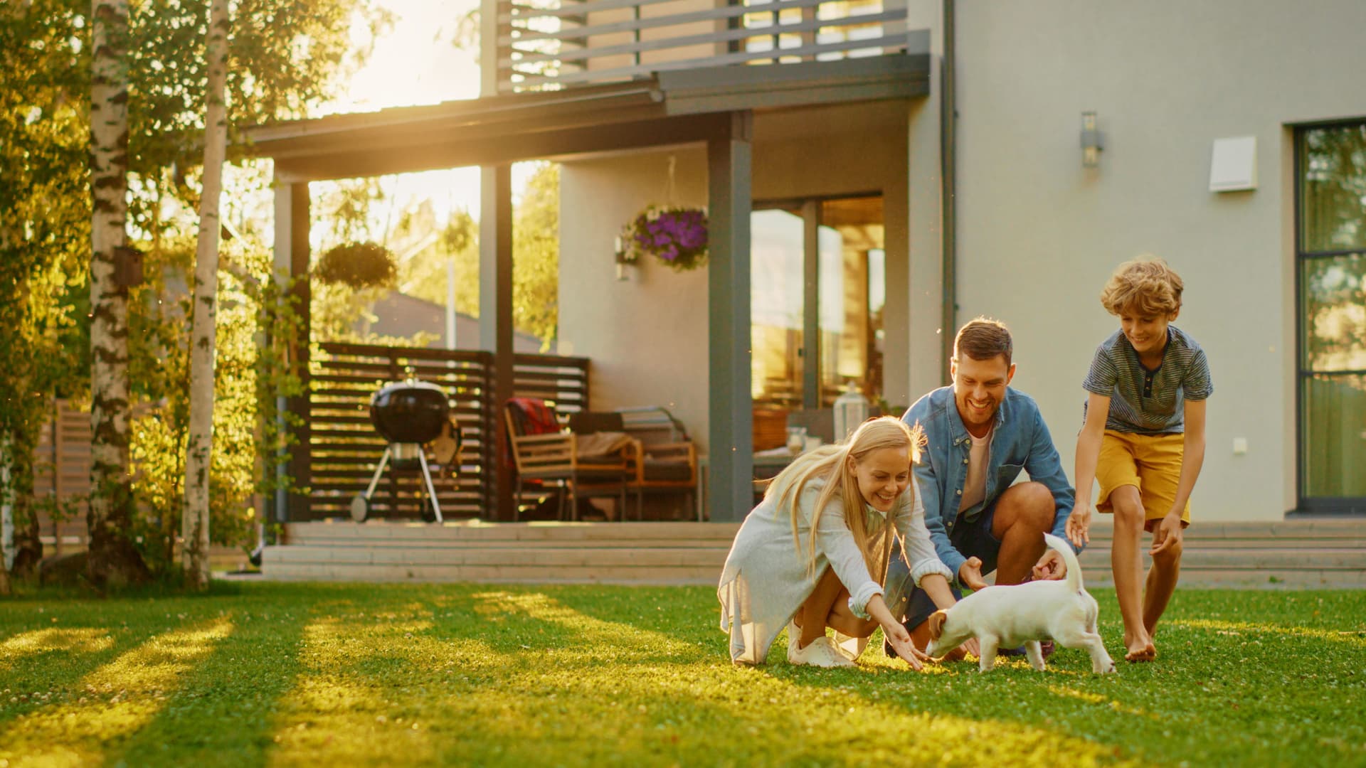 Familie mit Hund auf dem Rasen vor ihrem Haus.
