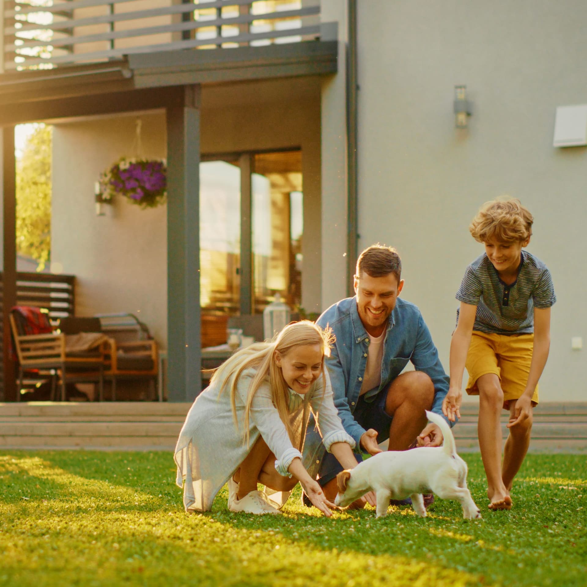 Familie mit Hund auf dem Rasen vor ihrem Haus.