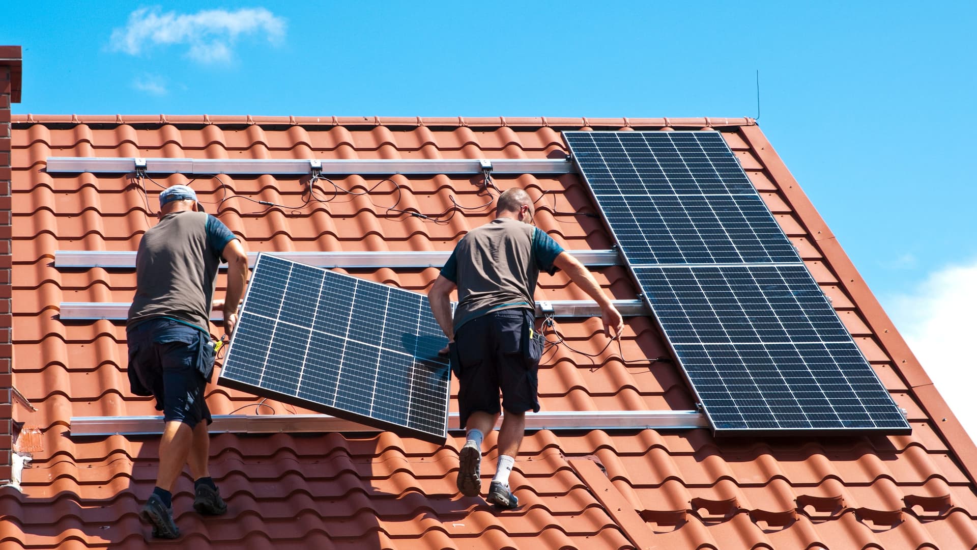 Zwei Handwerker beim Installieren von Solarpanels.