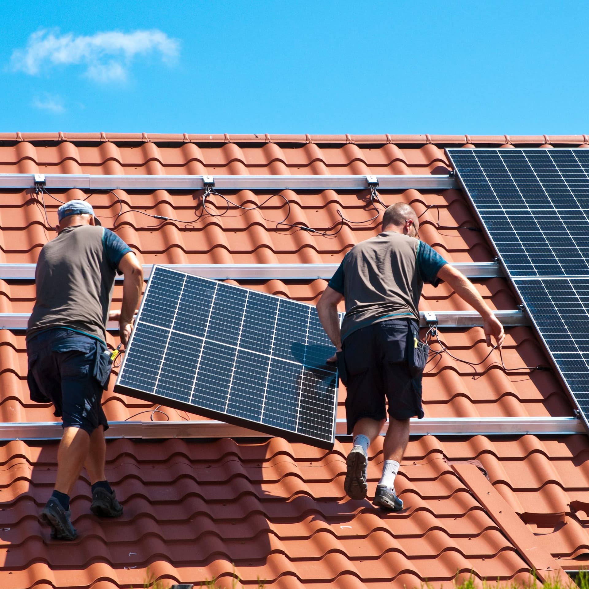 Zwei Handwerker beim Installieren von Solarpanels.