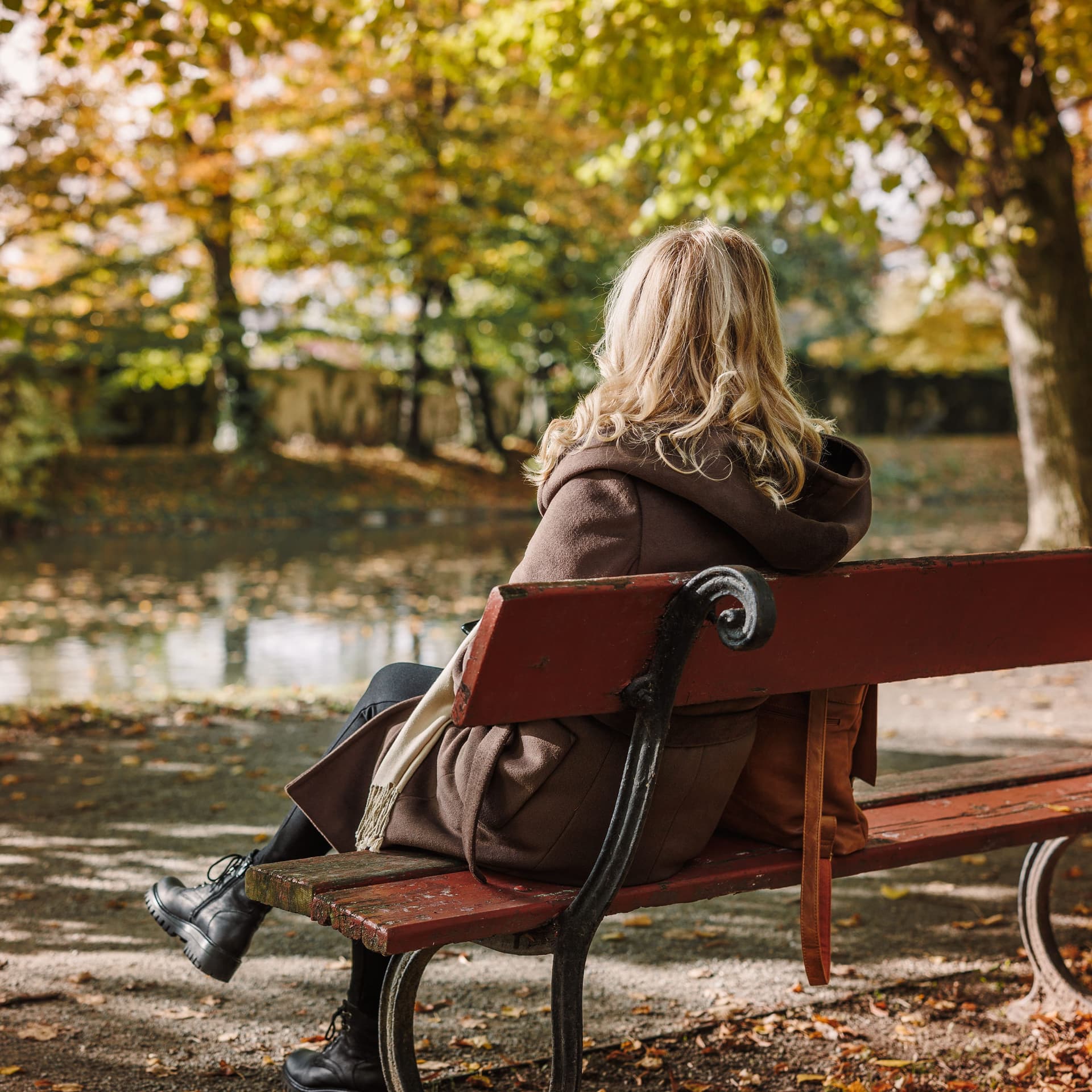Frau sitzt im Park auf einer Bank.