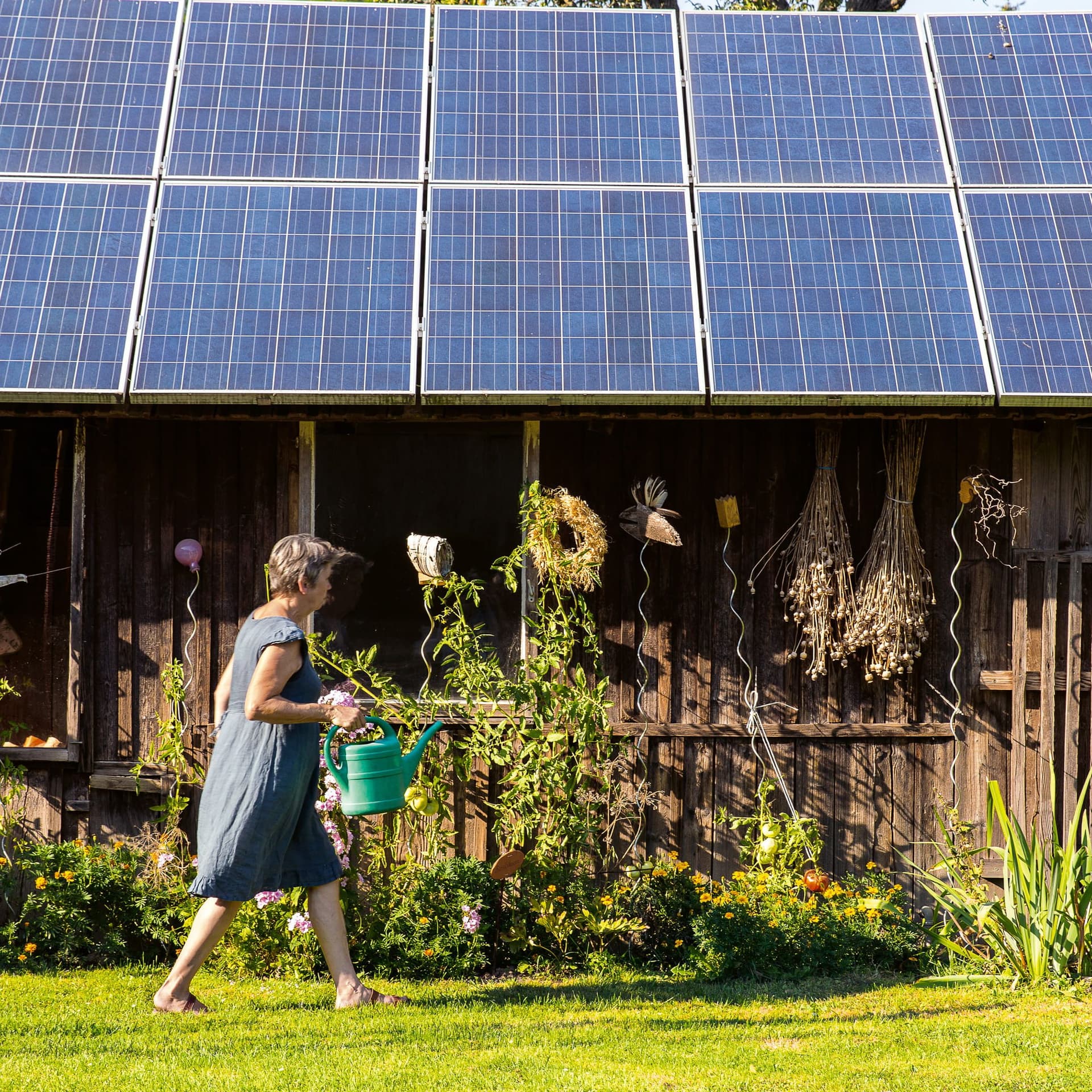 Frau vor einem Haus mit Solaranlage.