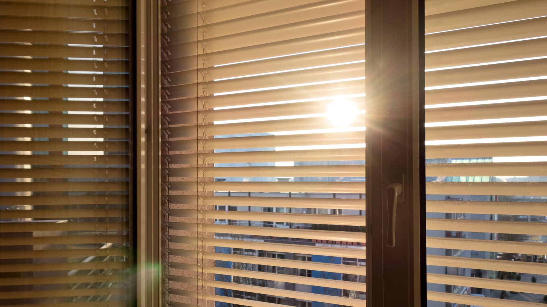 Sonne scheint hinter einer Jalousie hervor.