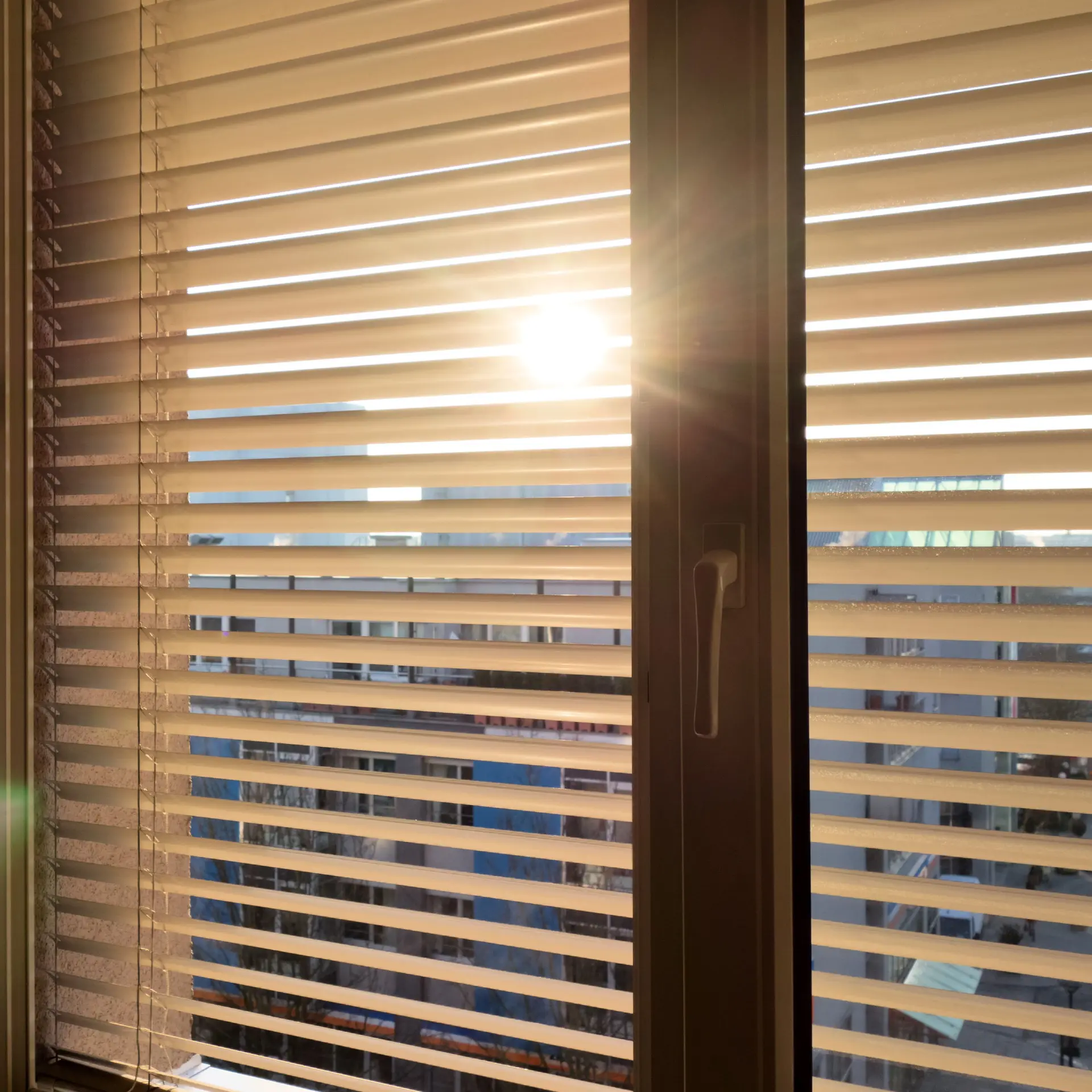 Sonne scheint hinter einer Jalousie hervor.