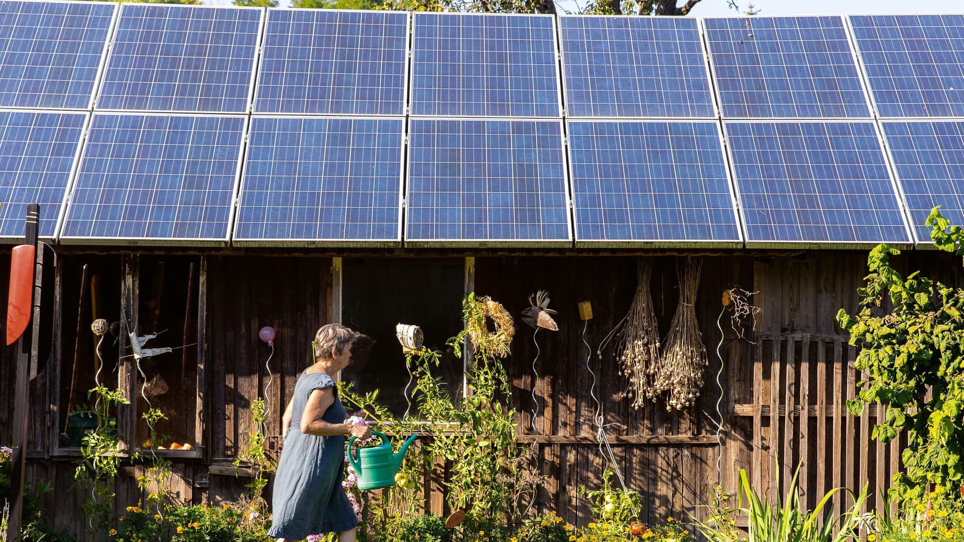 Frau vor einem Haus mit Solaranlage.